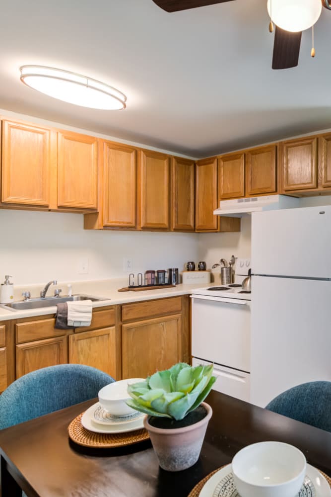 Staged kitchen with oak cabinets and white appliances, next to a dining nook at Mapleton Square Apartment Homes in Dover, Delaware