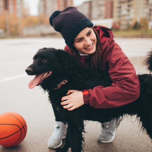 A resident hugging a dog on a basketball court at Silver Strand I in Coronado, California