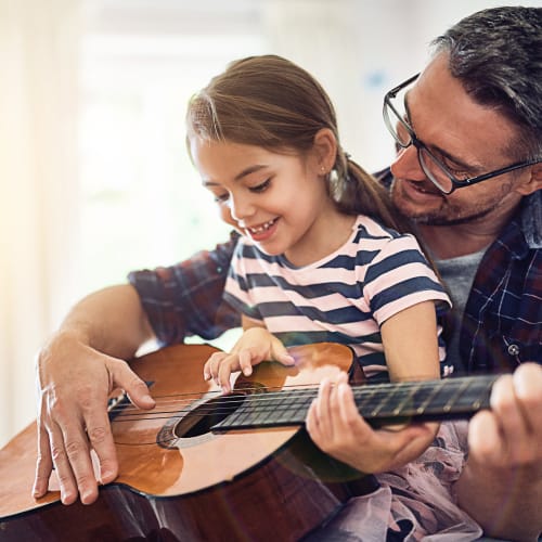A father playing guitar with her daughter at Beech St. Knolls in San Diego, California