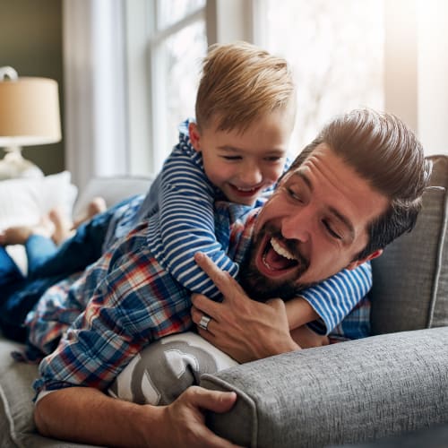 A father and his son playing on a couch in a home at El Centro New Fund Housing (Officers) in El Centro, California