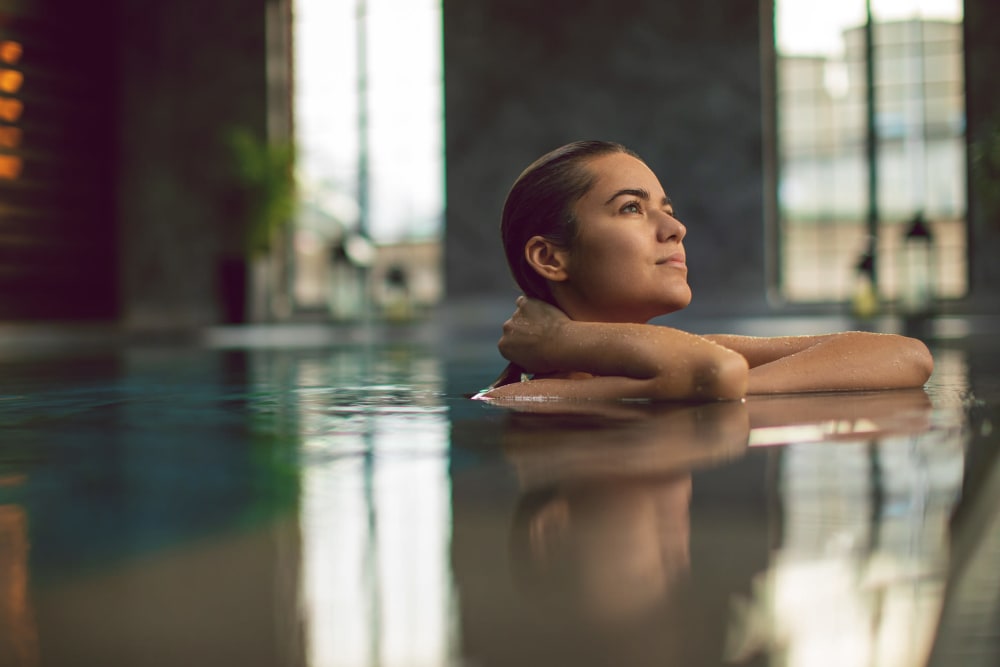 Resident relaxing at the indoor Infinity pool's edge at Tesoro Del Valle in Los Angeles, California