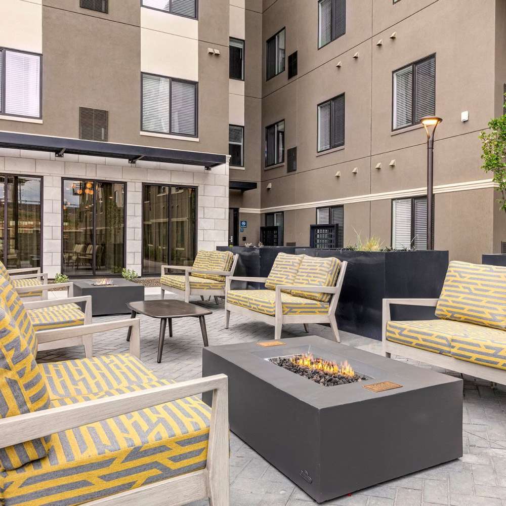 Outdoor lounge area with modern seating and fire pit, surrounded by apartment buildings at WaterWalk Boise - Meridian in Meridian, Idaho