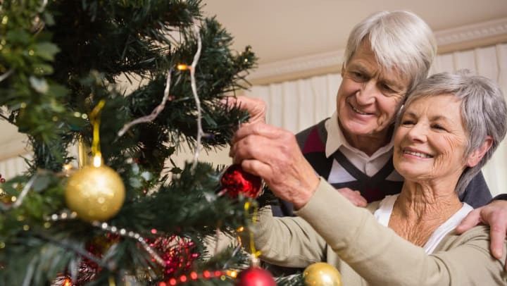 Image of an older couple decorating a Christmas tree.