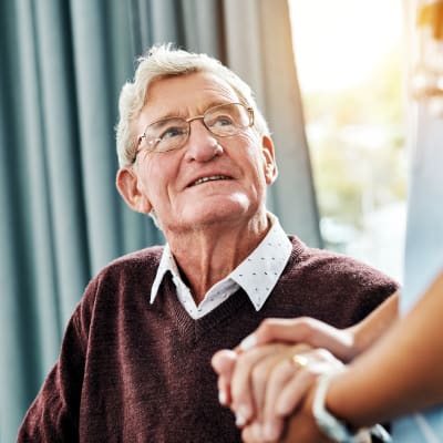 Resident holding hands with a caretaker at Willows Bend Senior Living in Fridley, Minnesota