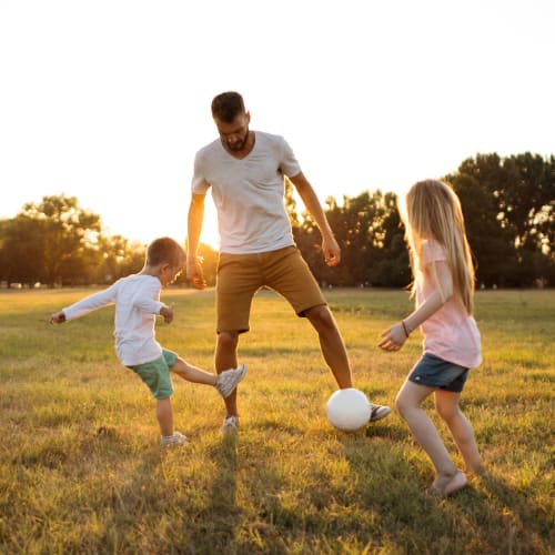 A father and his children playing in a park near The Village at Midway Manor in Virginia Beach, Virginia