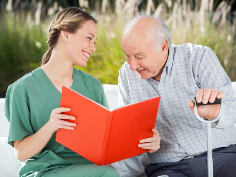 Caregiver sharing a book with a resident at Wellington Place at Fort Atkinson in Fort Atkinson, Wisconsin