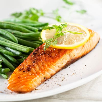 Grilled salmon with a slice of lemon and fresh green beans on a plate at Willows Bend Senior Living in Fridley, Minnesota