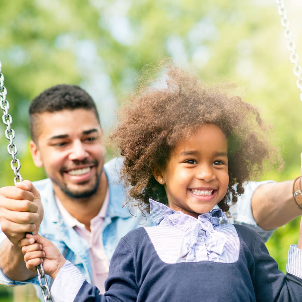 Father and daughter playing on the swings at The Belmont in Evans, Georgia