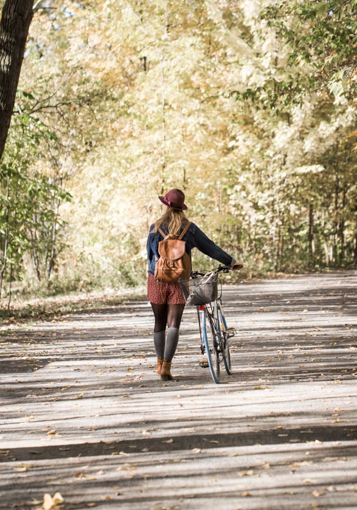 A woman walking her bike on a trail through the trees near Hunt Club in Gaithersburg, Maryland