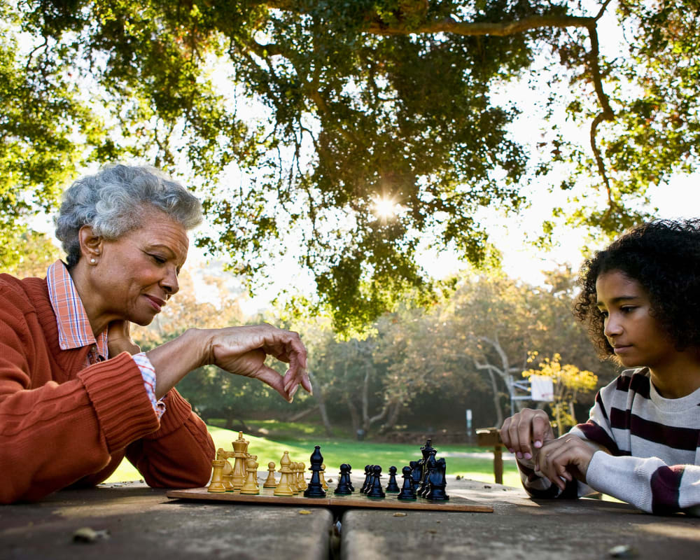 A resident playing chess with a child at Waverly Place in Albany, Oregon