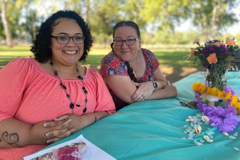 Two employees sitting outside at a table with a bouquet at Ray Stone Inc.