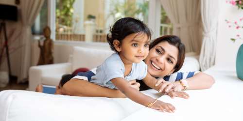 A cute baby with their mother lying on bed at Jefferson Cunningham Apartments in Los Angeles, California