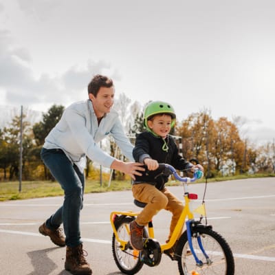 Man helping his son ride his bike at Park Sorrento in Bakersfield, California