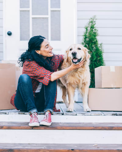 Woman seated on front steps with her dog and moving boxes near A Storage Place