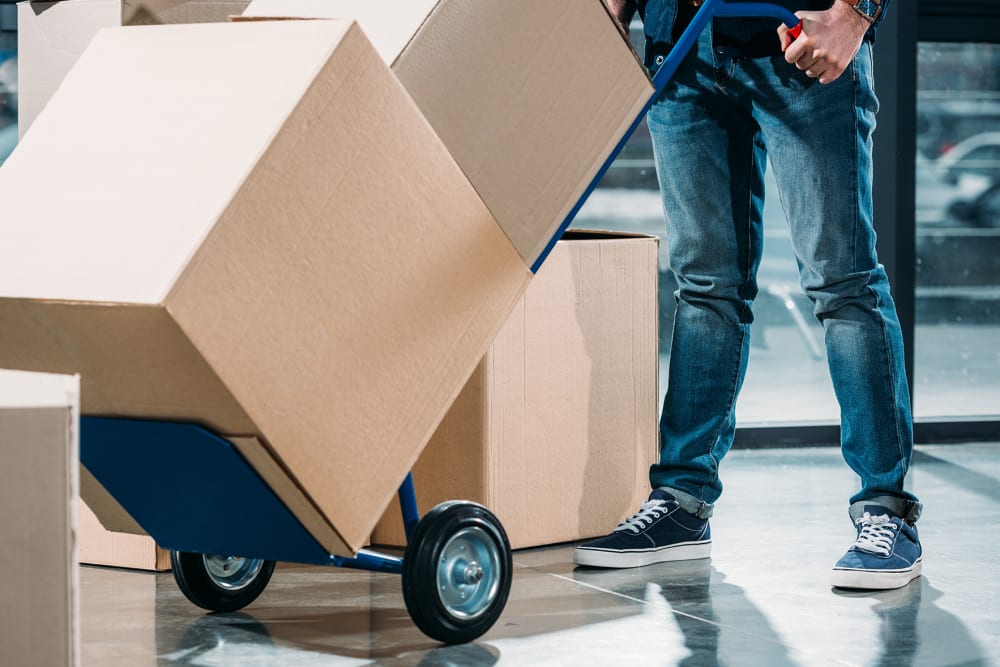 Man pushing boxes on a dolly at A-American Self Storage in Pomona, California