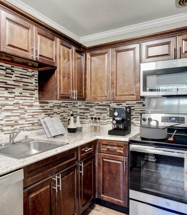 Modern kitchen with light wood cabinetry and custom tile backsplash in a model home at Heritage at Shaw Station in Washington, District of Columbia