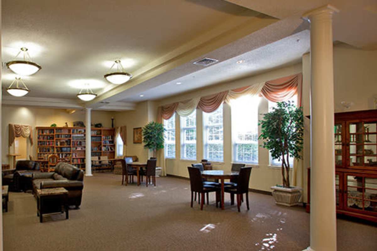 Cozy community lounge with bookshelves, comfortable seating, and natural light from large windows at Evergreen Senior Community in Bowie, Maryland
