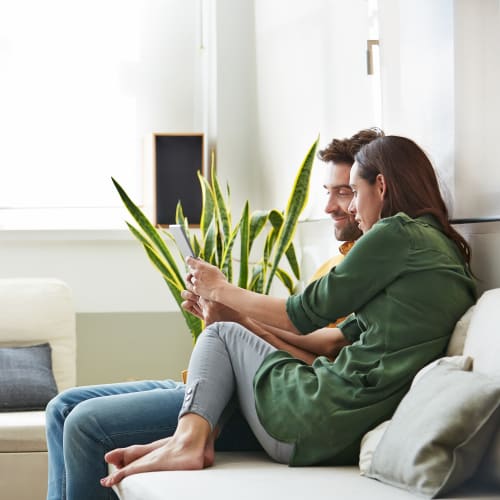 A couple setting on the couch and holding and iPad at Prospect View in Santee, California