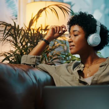 Woman sitting on a couch with headphones on moving her arms to the music at Cypress Creek at Lakeline in Cedar Park, Texas