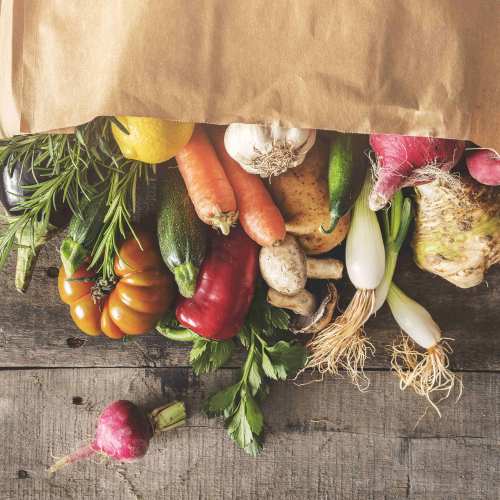 Colorful assortment of fresh vegetables spilling from a paper bag onto a wooden surface at Valley View Gardens in Dunlap, Tennessee