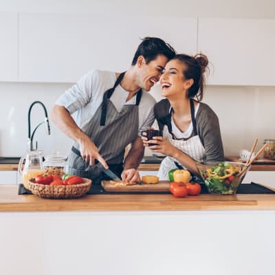 Man and woman cooking and laughing together in a kitchen at Claremont Towers in Hillsborough, New Jersey