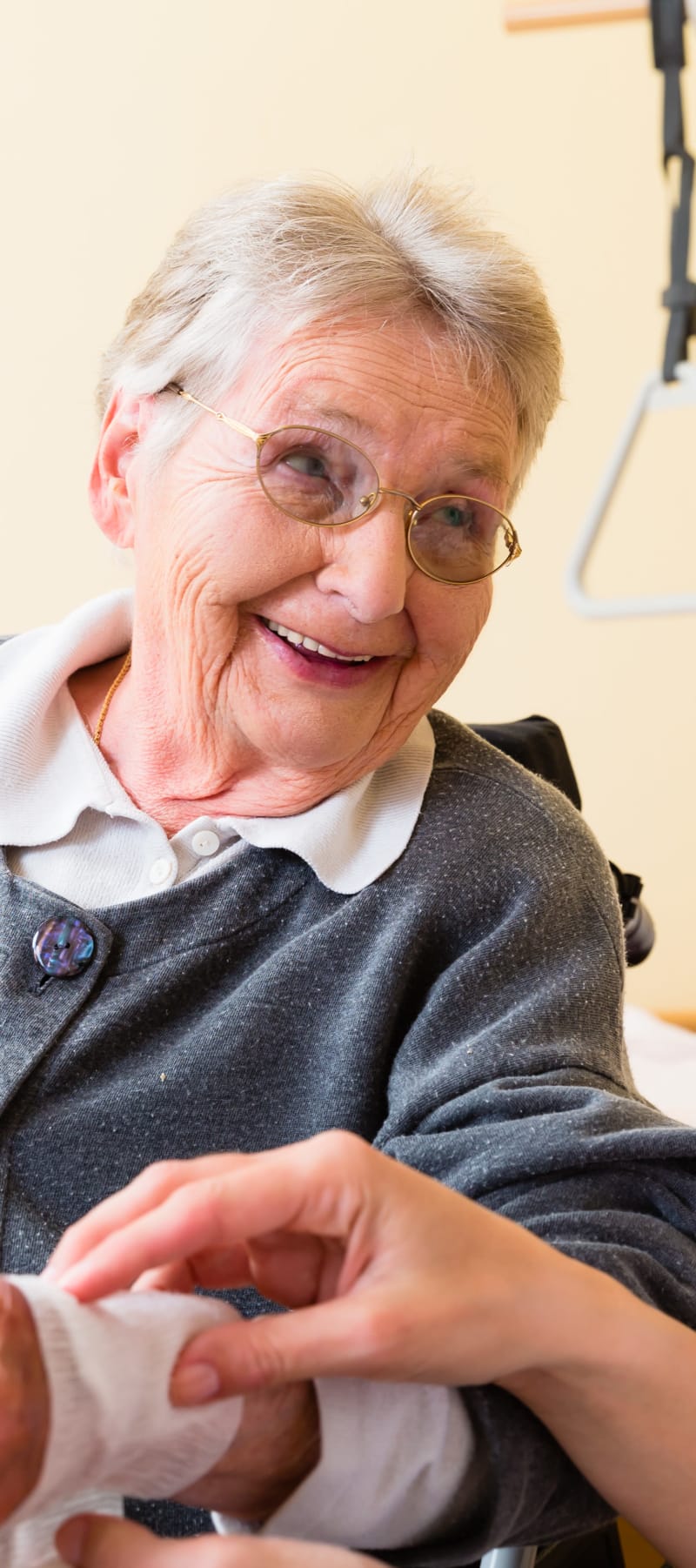 Caretaker mending a wound on a residents wrist at East Troy Manor in East Troy, Wisconsin