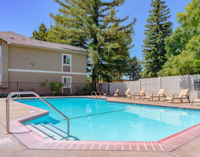 Large community swimming pool with multiple sun loungers to relax at Woodlake Close in Sacramento, California