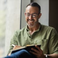 A man writing in a notebook at Retreat at Fairhope Village in Fairhope, Alabama