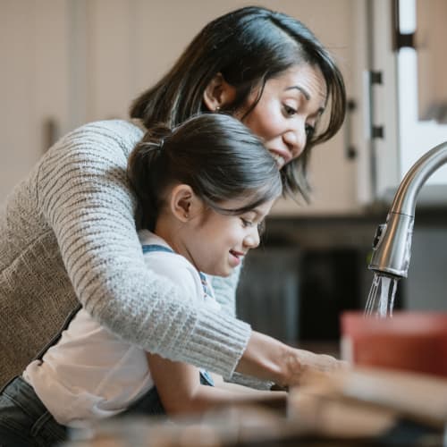 A mother helping her wash dishes in a home at Perry Circle Apartments in Annapolis, Maryland