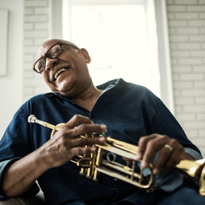 Laughing resident holding a trumpet at Atlas Point at Prestonwood in Carrollton, Texas