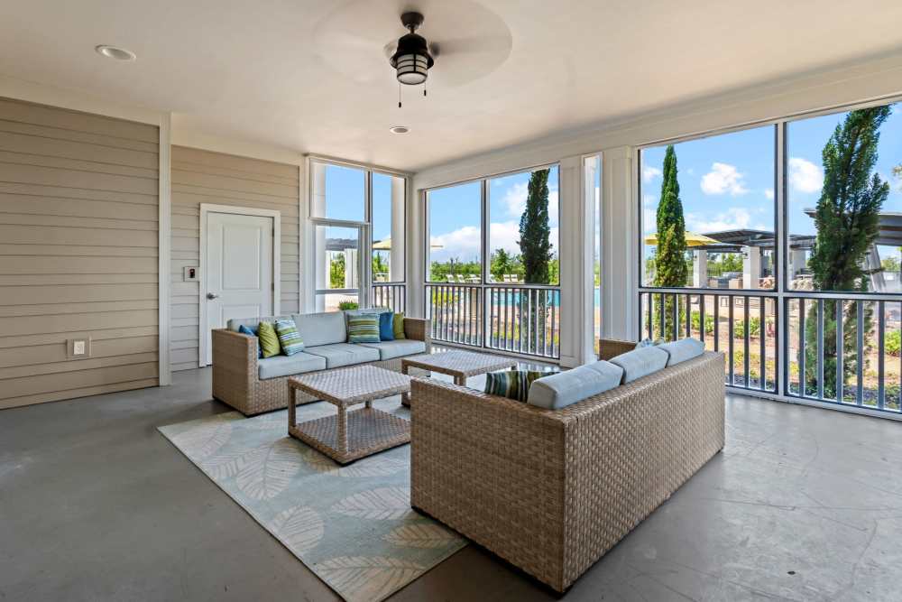 Outdoor lounge with screened in seating area and ceiling fan at Mexico Beach Crossings Apartments.
