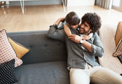 Resident dad and daughter talking on the couch at The Fairways Apartment Homes in Lee's Summit, Missouri