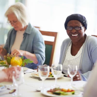 A resident smiling while enjoying a meal at The Sanctuary at Brooklyn Center in Brooklyn Center, Minnesota