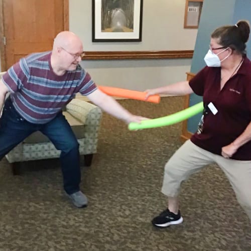 A masked team member playing with a resident at Glen Carr House Memory Care in Derby, Kansas