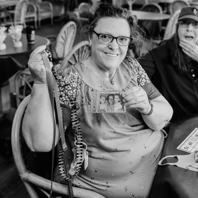 Resident at Bingo Night showing off a photo of her family at Cascade Park Adult Day Health in Tacoma, Washington