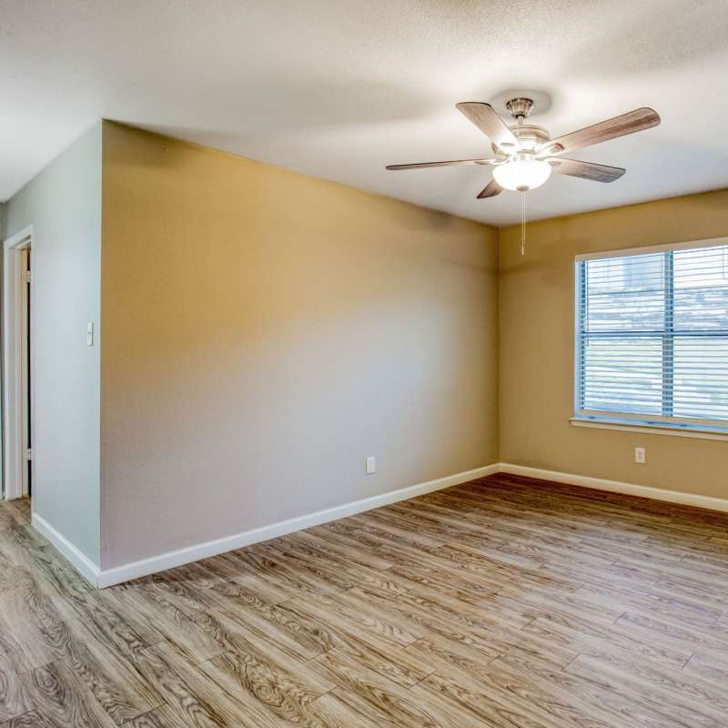 Spacious living room with windows and ceiling fan at The Summit Apartments in Athens, Texas