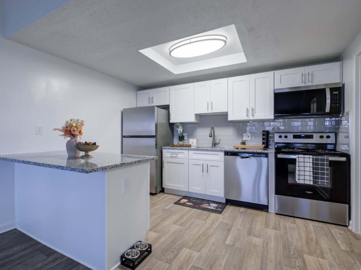 Bright kitchen with white appliances, wood cabinets, and laminate counters at Applegate Apartments in Muncie, Indiana