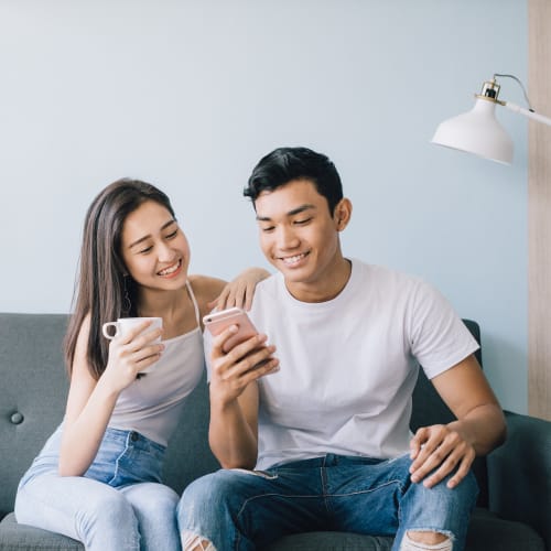 Happy couple setting on the couch and checking the phone at Breezy Point in Norfolk, Virginia