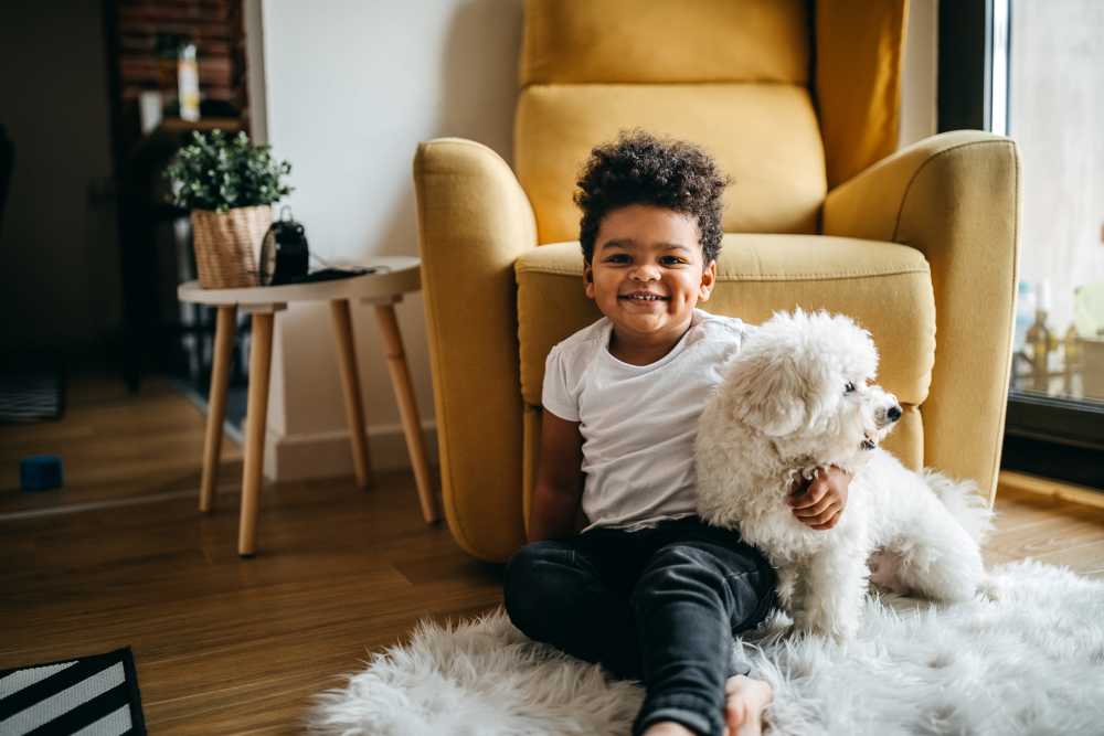 Child sitting on a rug next to a fluffy white dog in the apartment at Copper River in Spokane,Washington