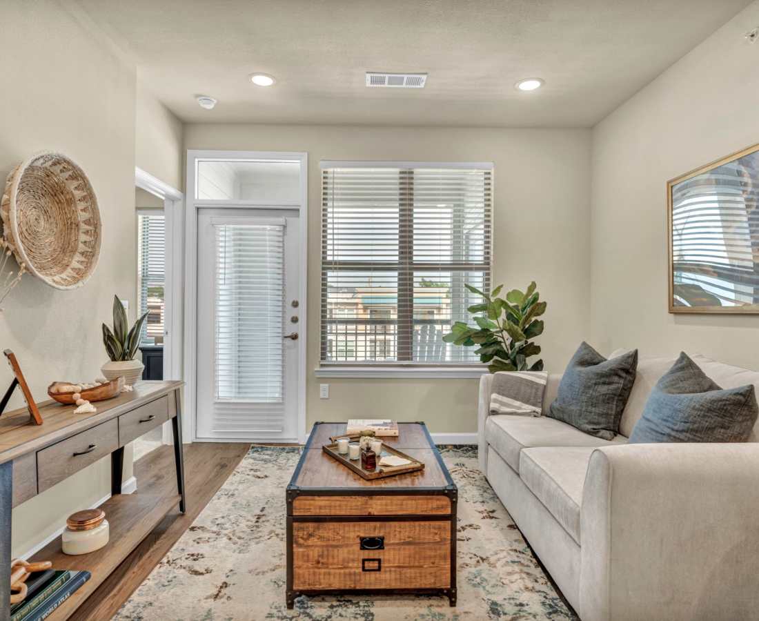 Plants and books on a small coffee table in front of the couch in a model apartment at Cypress Creek at South Cedar in Temple, Texas