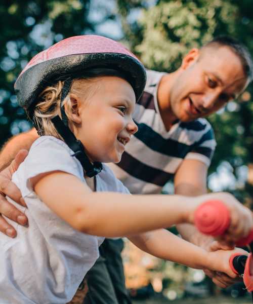 A father helping his child ride a bike near Copper Steppe in Parker, Colorado