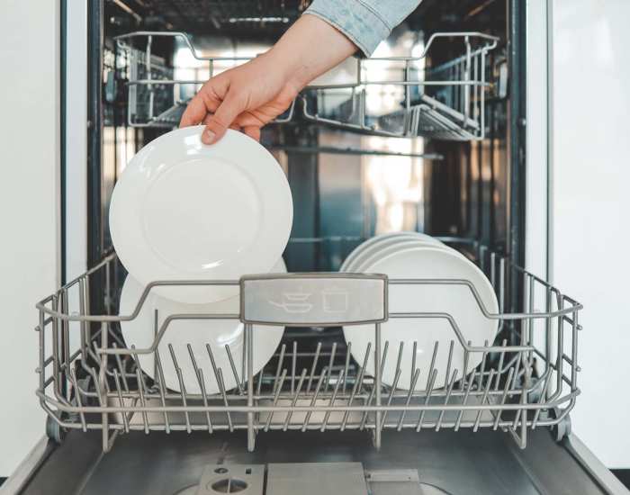 Resident using the diswasher in her apartment home at Meadowview Apartments in Anoka, Minnesota