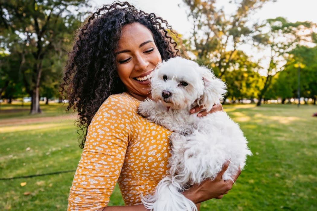A woman holding her small dog at a park near Boynton Gardens Apartments in San Jose, California