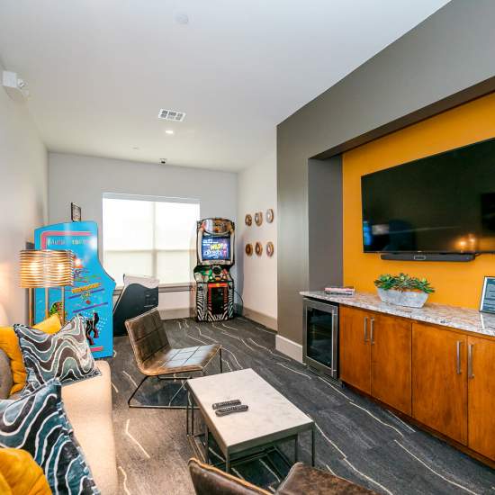 Community clubhouse with large couch, arcade games and flat screen television at NOVU New Forest in Houston, Texas