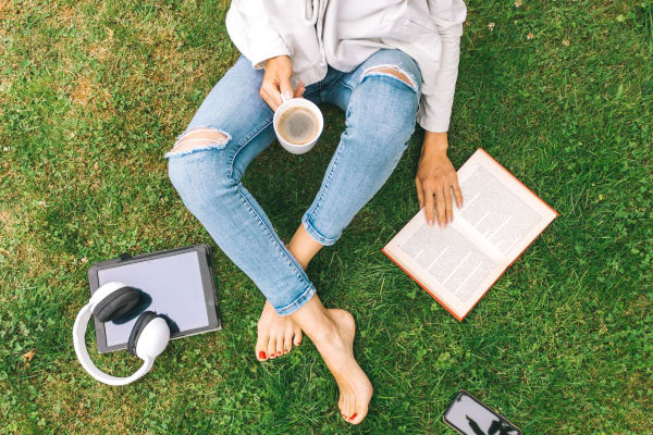 Resident reading in the grass outside her apartment at Parkside Towns in Richardson, Texas