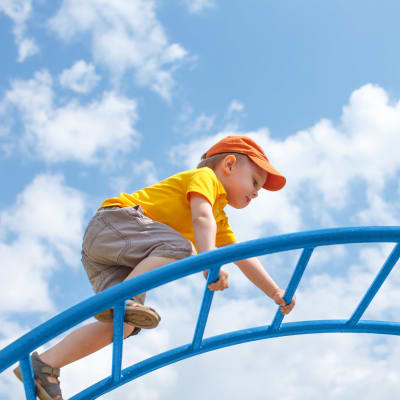 A child playing on a jungle gym at a playground at Santo Terrace in San Diego, California