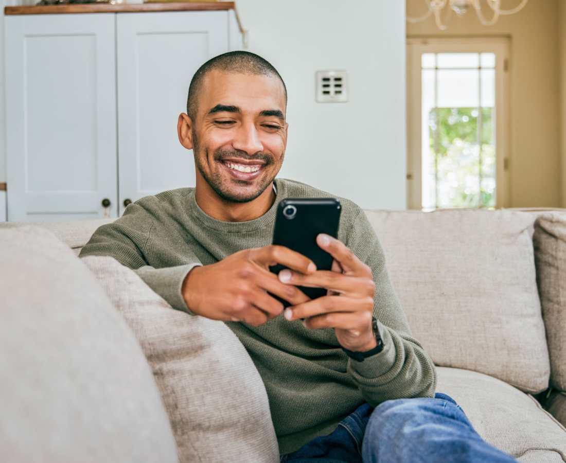 Resident looking at his phone in his living room at Delta View Apartments in Antioch, California