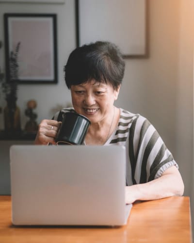 Resident on laptop drinking coffee Trustwell Living at Oakley Place in Greenville, Ohio