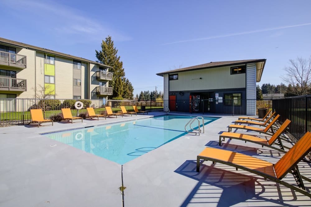 Large swimming pool with lounge chairs surrounding at Terra Apartment Homes in Federal Way, Washington