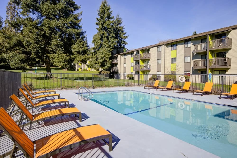 Large swimming pool with lounge chairs at Terra Apartment Homes in Federal Way, Washington